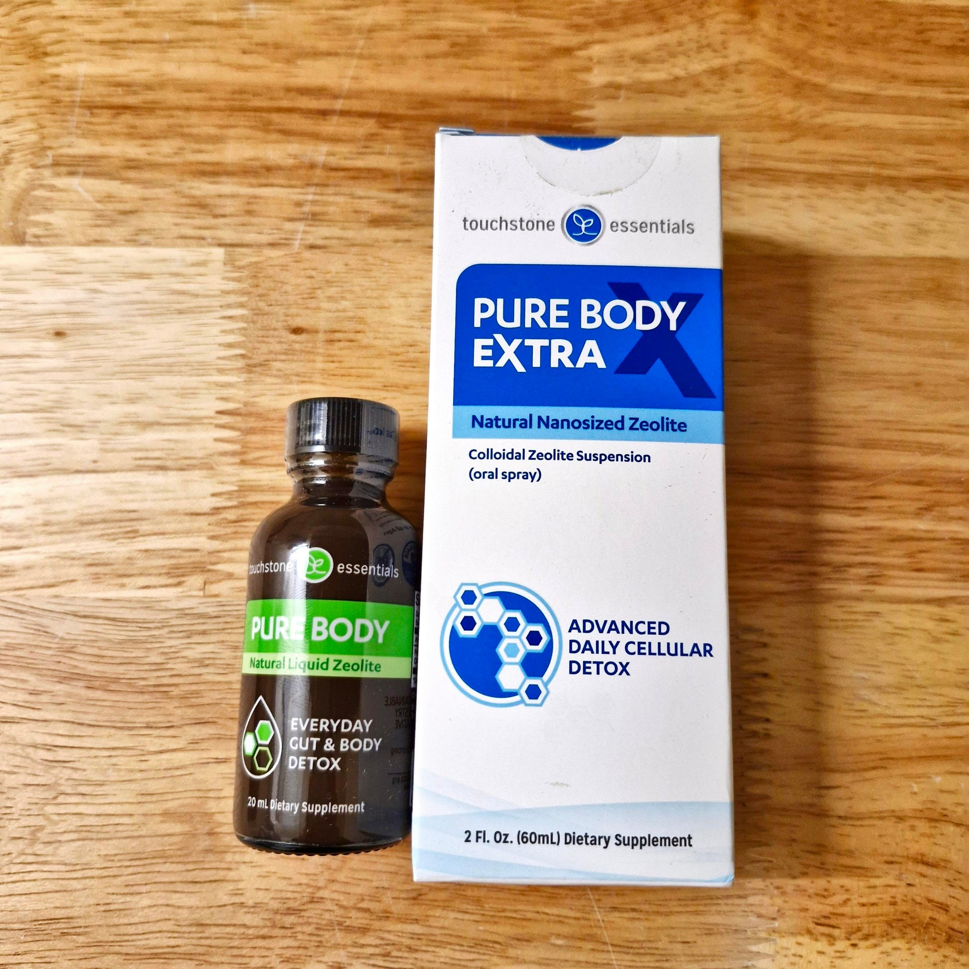 Bottle and box of Pure Body Extra supplement on a wooden surface